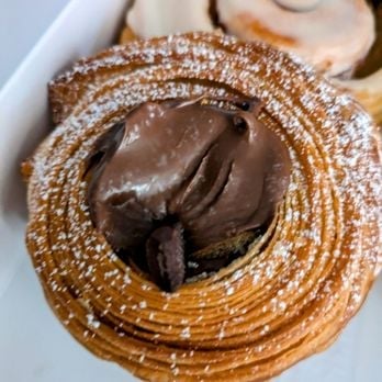 Chocolate-filled pastry spiral dusted with powdered sugar on white plate