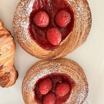 Two pastry tarts filled with red raspberries and dusted with powdered sugar
