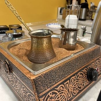 Traditional copper coffee brewing set on decorative stand with ornamental patterns