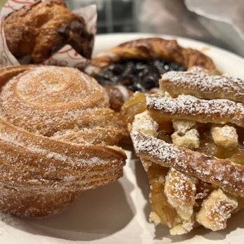 Assorted churros and pastries dusted with sugar and cinnamon on a white plate
